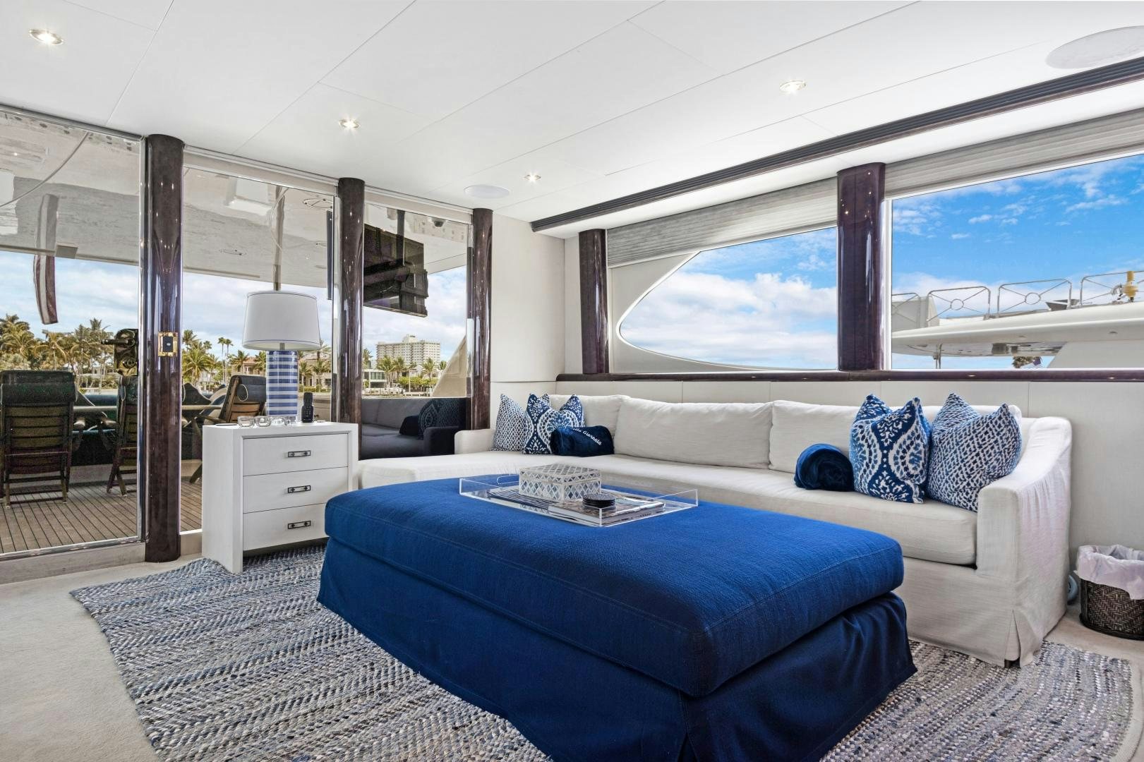 a large living room with a large blue couch and a large window aboard BELLA GIORNATA Yacht for Sale