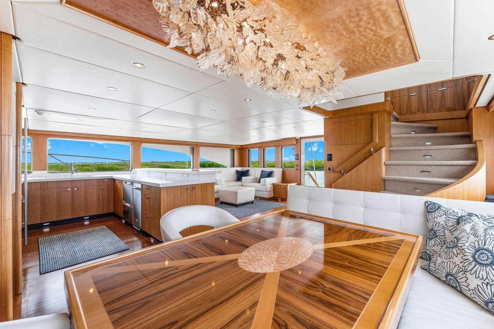 a large living room with a large wood table and a large chandelier aboard No Name Yacht for Sale