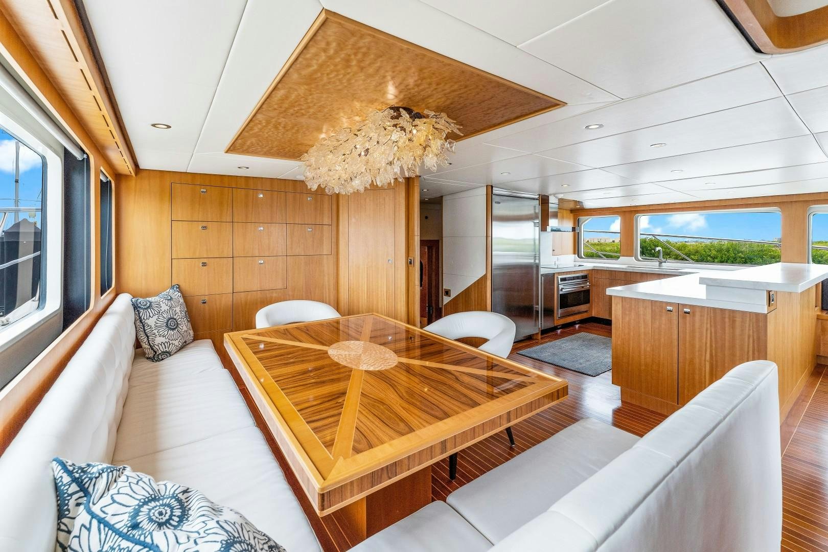 a large living room with a wood table and a large chandelier aboard No Name Yacht for Sale