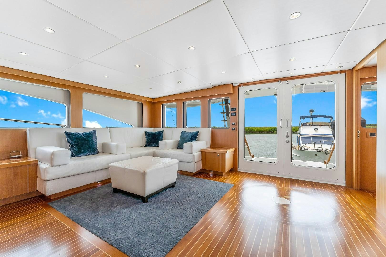 a living room with a large blue rug and white couches aboard No Name Yacht for Sale
