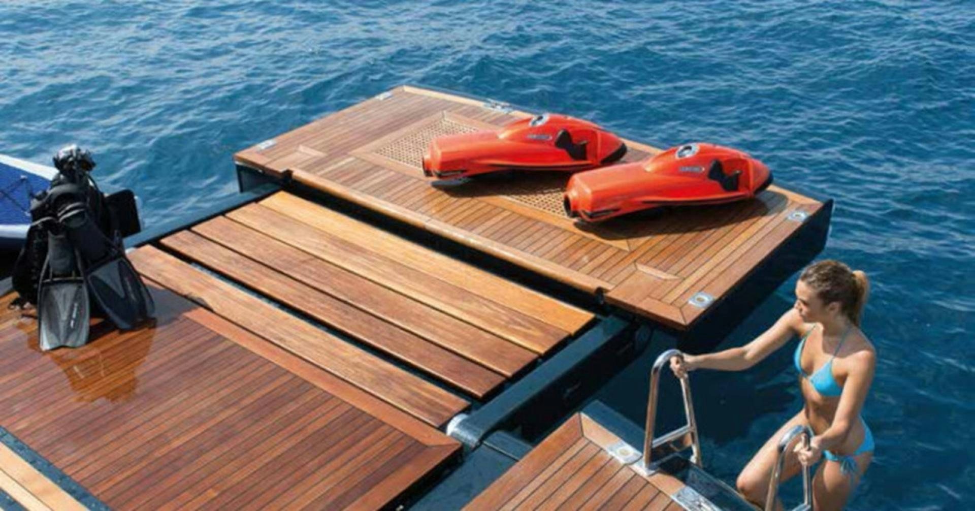 a woman in a bikini on a deck looking at a boat aboard HIGHLANDER Yacht for Sale