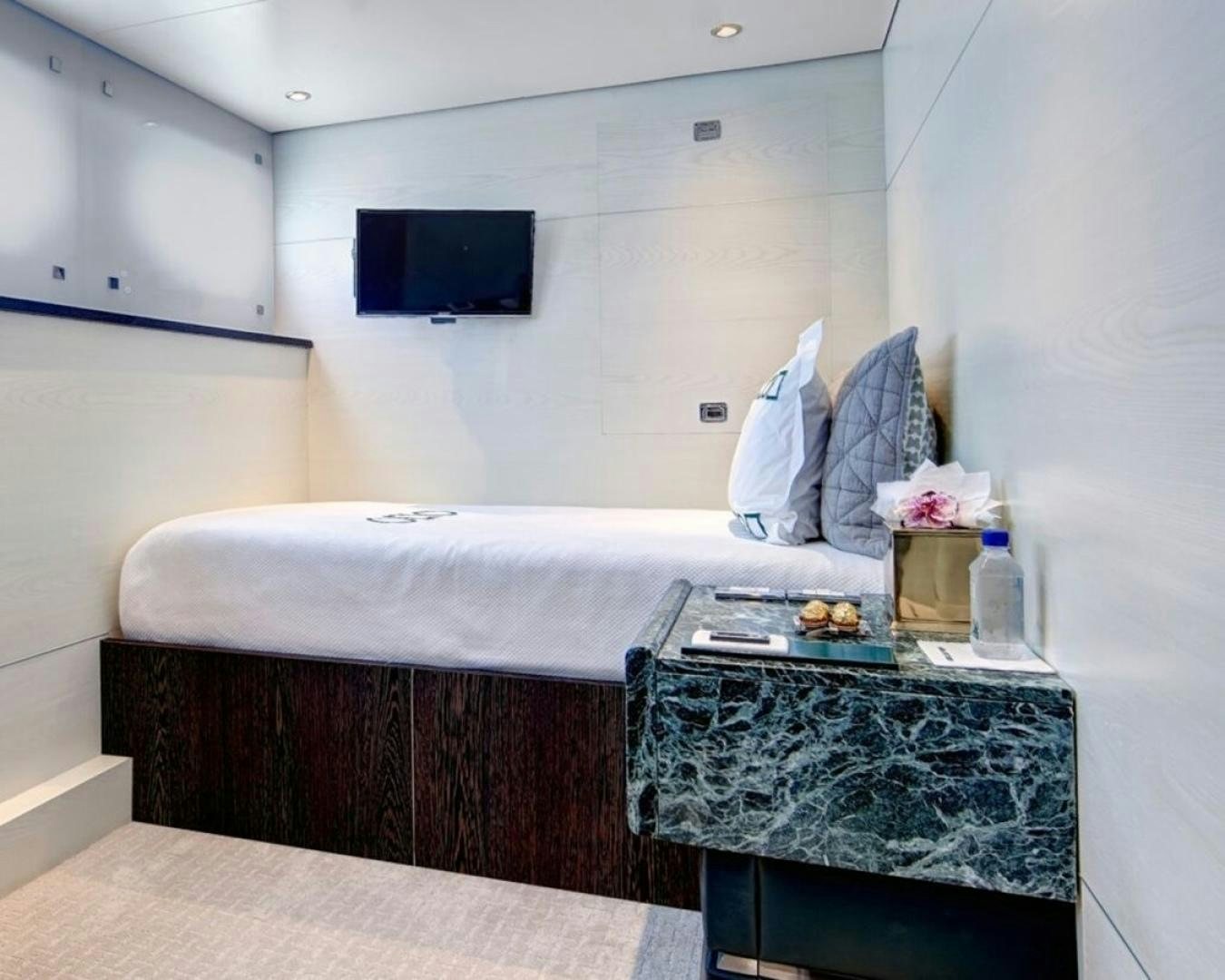 a bed with a table and tv aboard HIGHLANDER Yacht for Sale