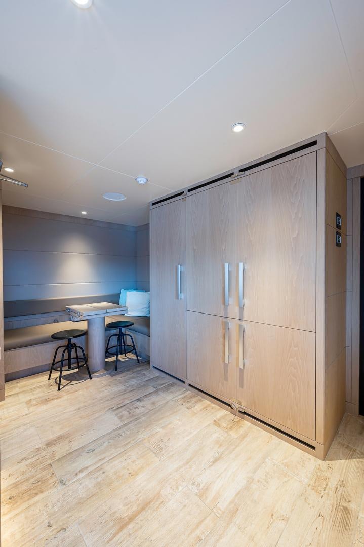 a room with a wood cabinet and a table and chairs aboard LIRA Yacht for Sale