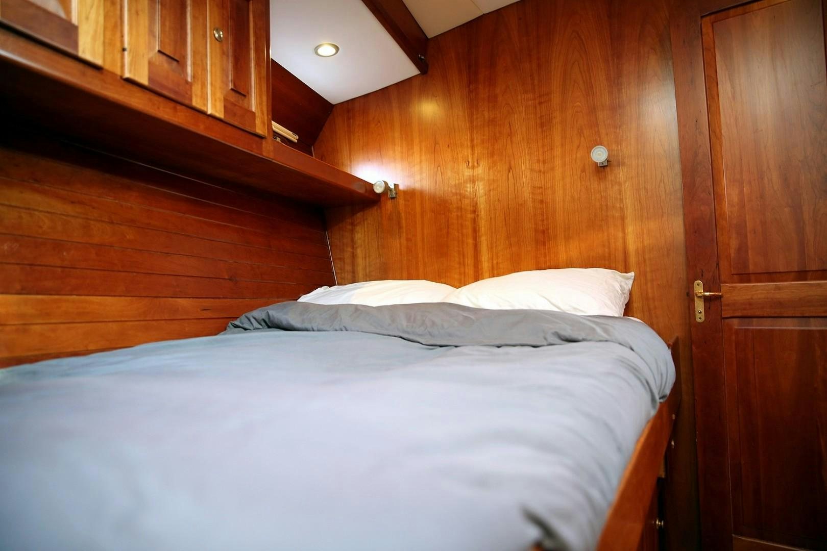 a bed with a white comforter aboard DANCIN BARE V Yacht for Sale