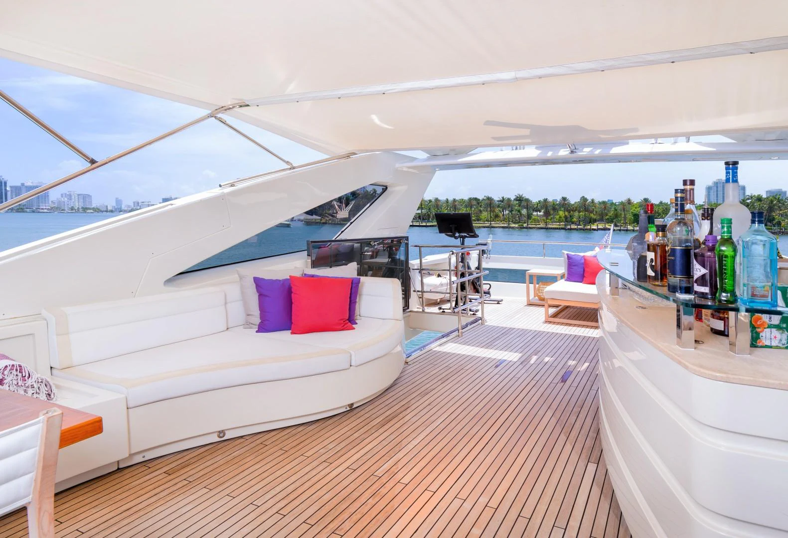 a room with a view of a body of water and a deck with a boat and a table aboard CASUAL Yacht for Sale