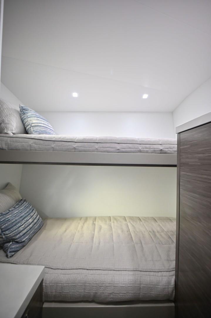 a bed with a white wall aboard Fish Tank Yacht for Sale