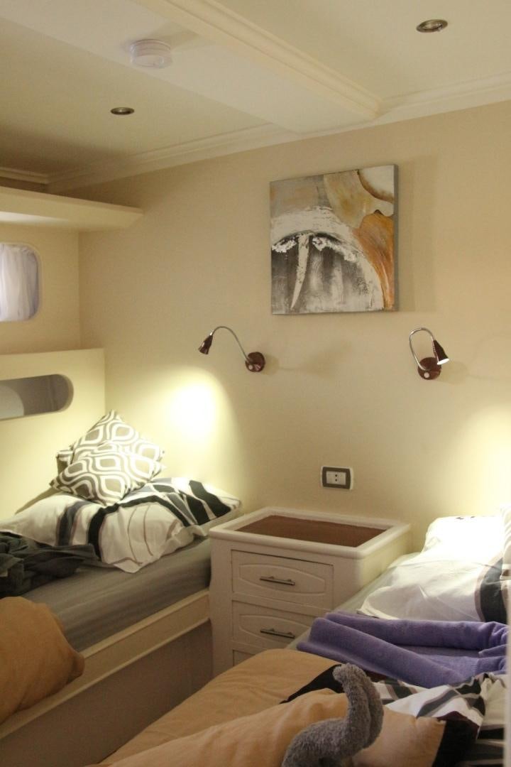 a bedroom with a bed and a dresser aboard SIM SIM Yacht for Sale