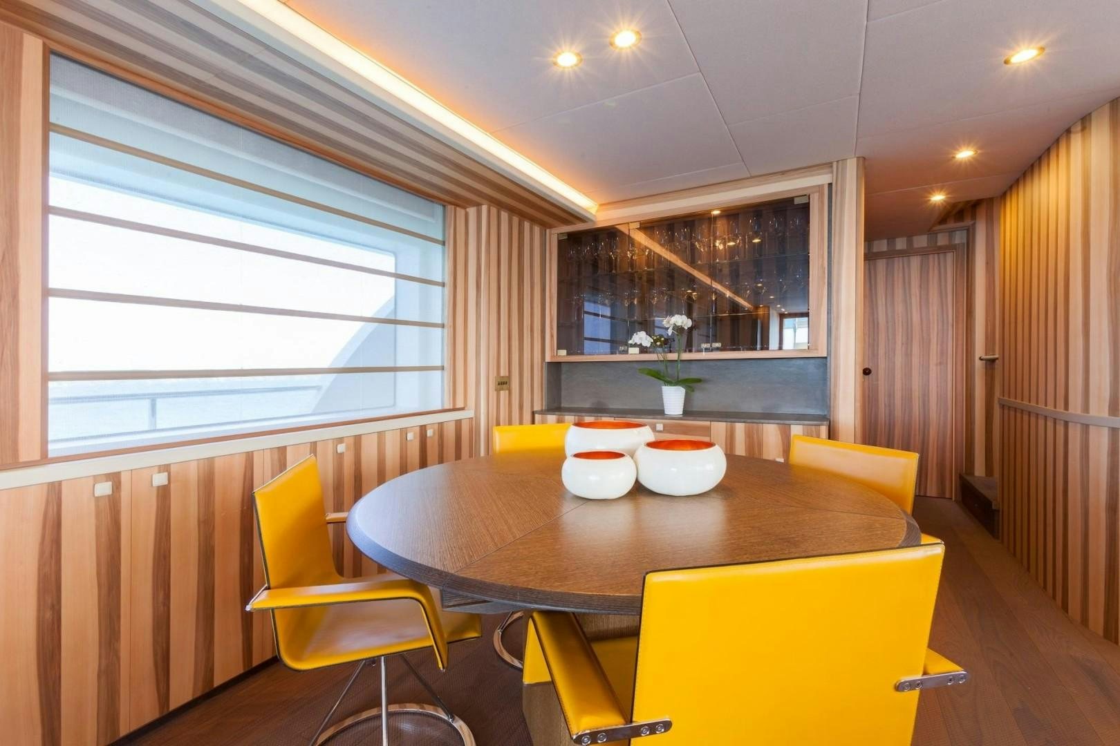 a dining table with chairs and a window aboard ACALA Yacht for Sale