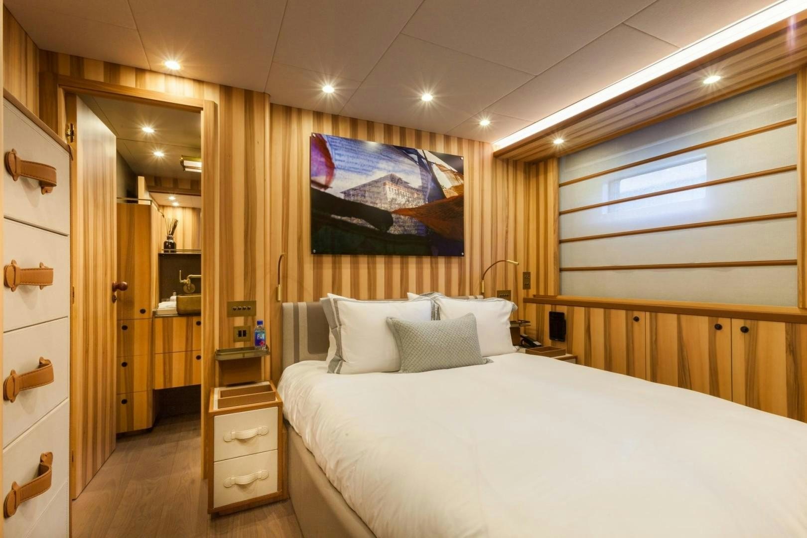 a bedroom with a bed and a painting on the wall aboard ACALA Yacht for Sale