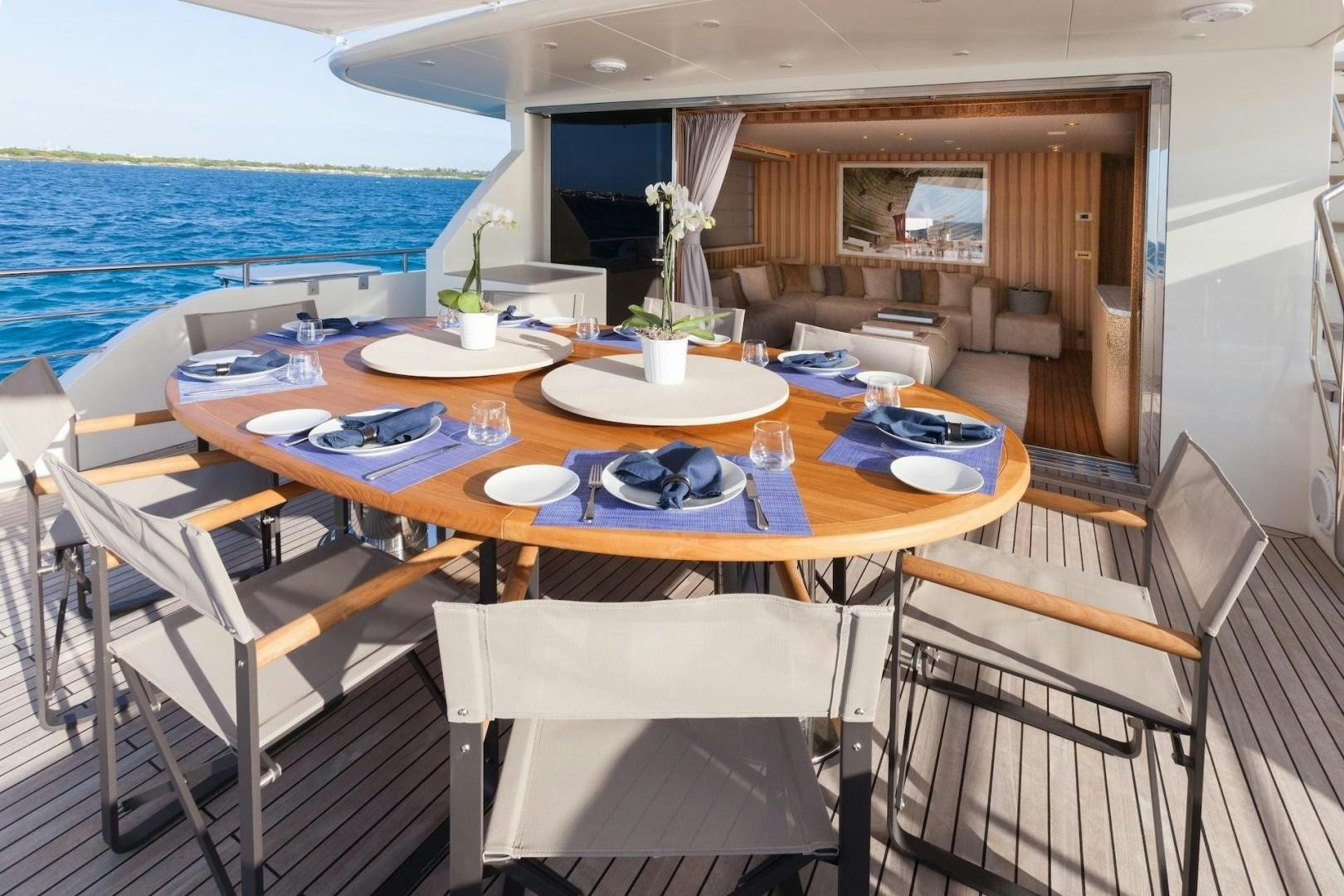 a table with plates and chairs on it next to a body of water aboard ACALA Yacht for Sale