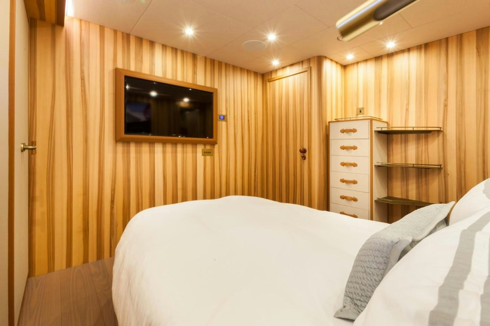 a bedroom with a wood wall aboard ACALA Yacht for Sale