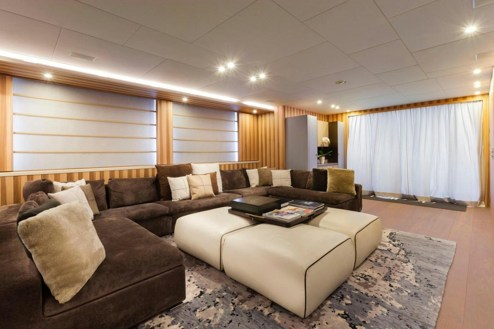 a person sitting on a couch in a large living room aboard ACALA Yacht for Sale