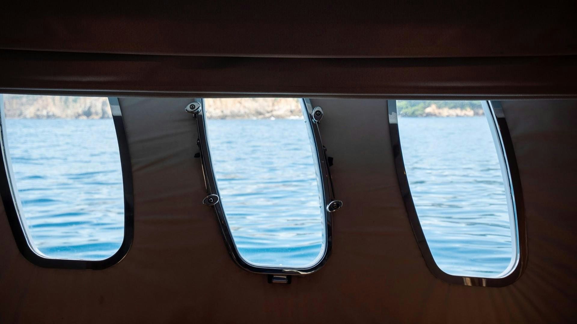 a window with a view of the ocean and land below aboard LUCKY Yacht for Sale