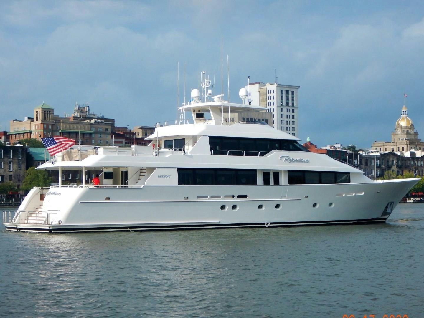 a large white boat in a harbor aboard REBELLIOUS Yacht for Sale