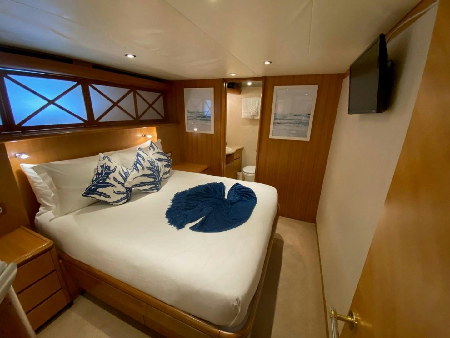 a bedroom with a blue blanket on the bed aboard EQUINOX X Yacht for Sale