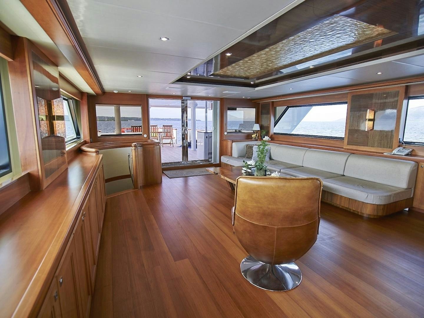 a room with a wood floor and a couch and a table with a plant on it aboard ALAIA Yacht for Sale