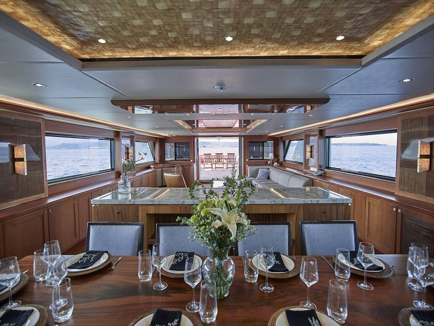 a large room with a table and chairs and a large window aboard ALAIA Yacht for Sale