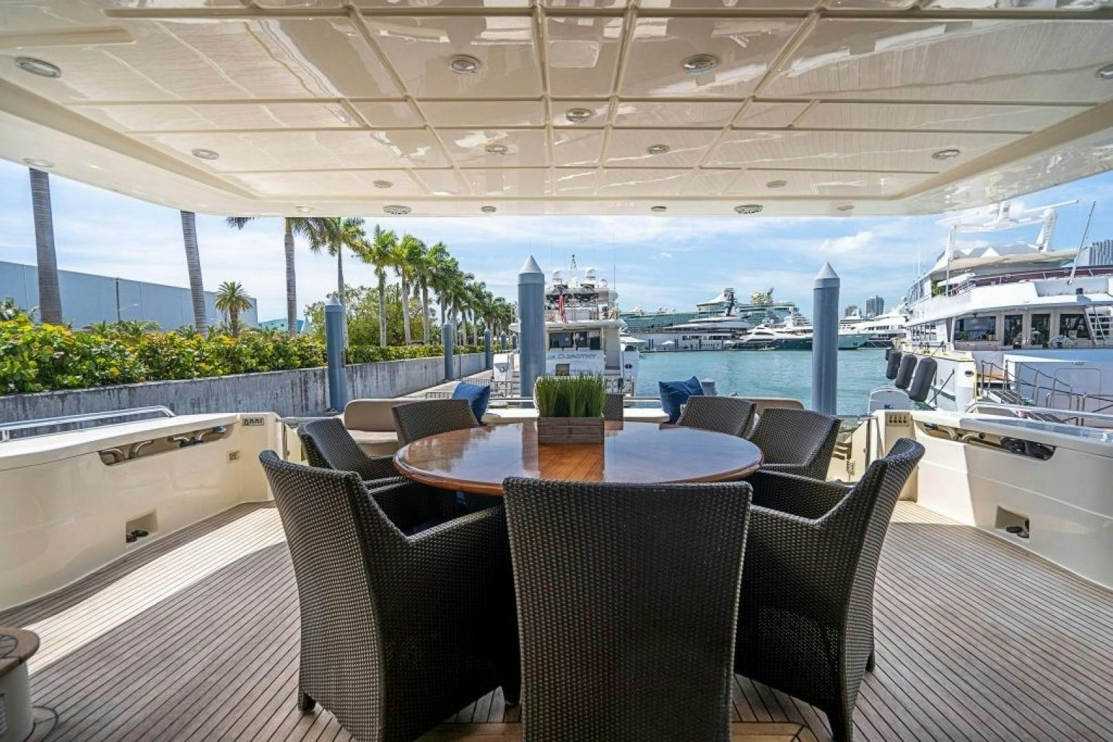a table and chairs on a deck overlooking a large ship aboard CINQUE MARE Yacht for Sale