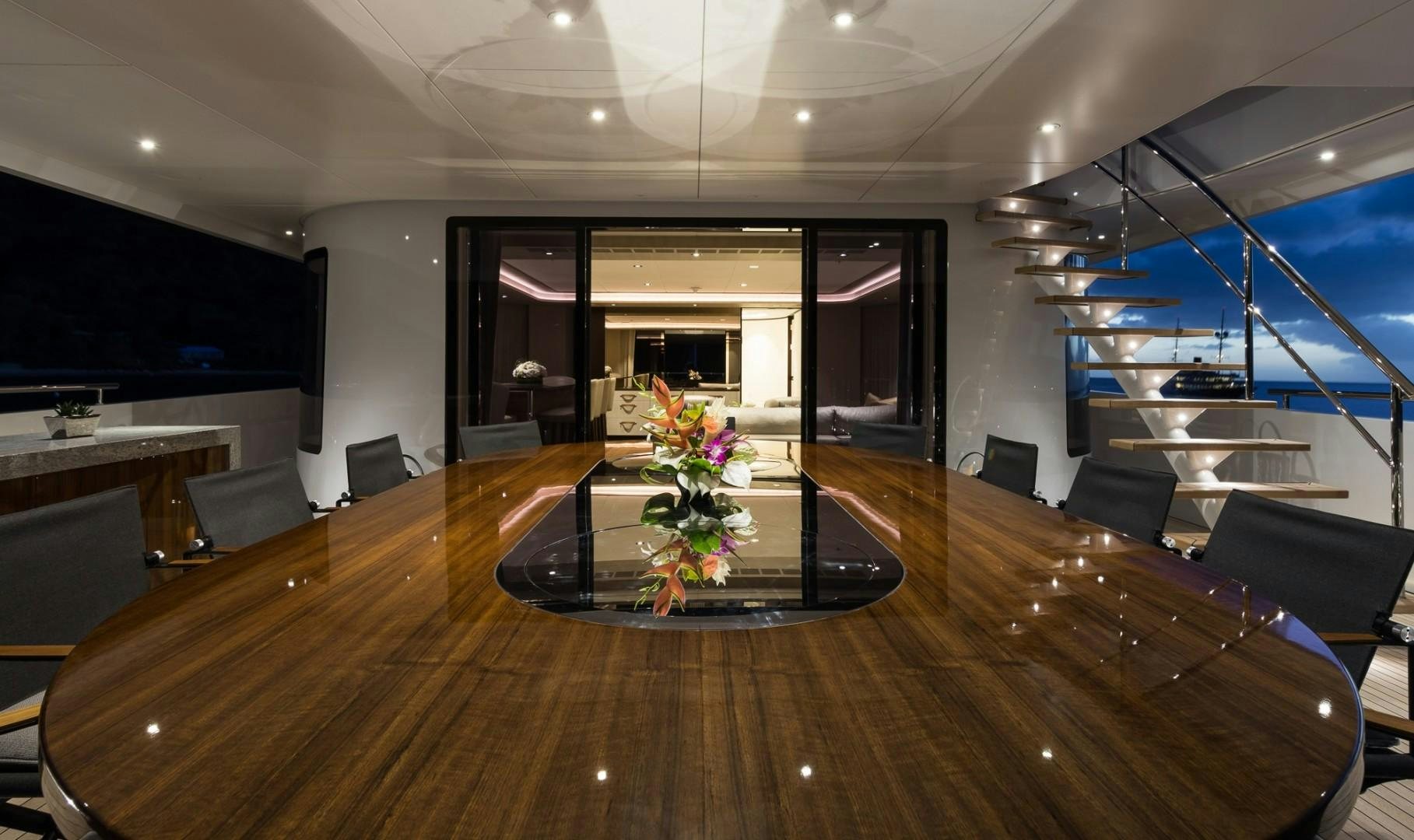 a room with a wood floor and a large wood table with chairs and a large screen on the aboard LAURENTIA Yacht for Sale