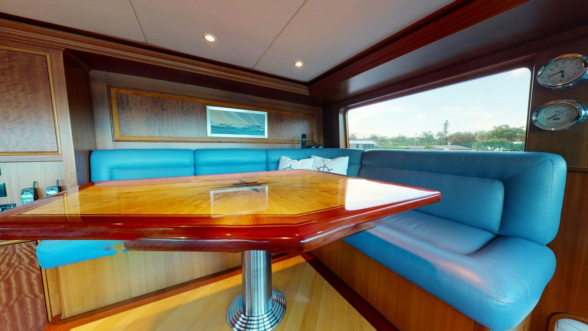 a table with a couch and a couch in a room with a window aboard PATRIOT Yacht for Sale