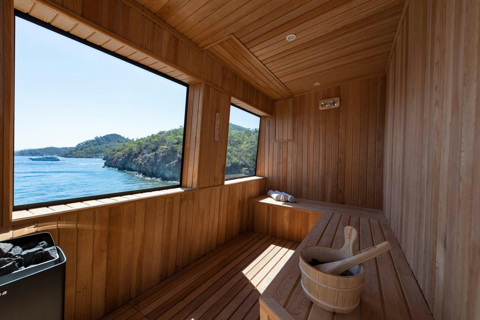 a room with a large window and a wood deck with a view of the ocean aboard OCEAN BREEZE Yacht for Sale