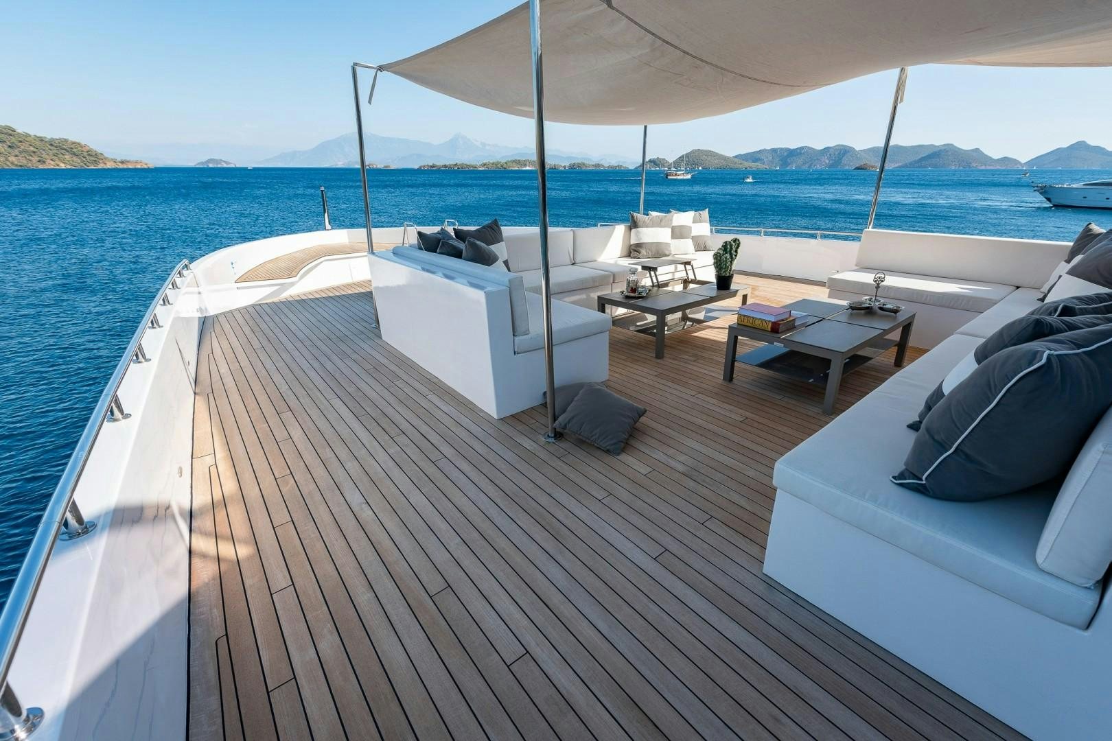 a deck with a view of the ocean and a large boat aboard OCEAN BREEZE Yacht for Sale