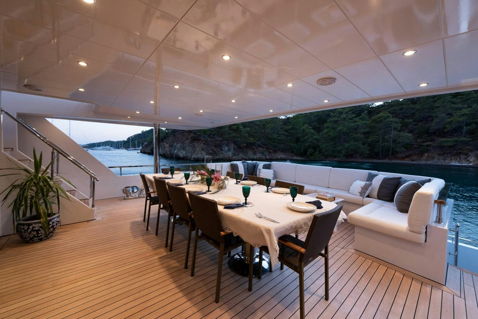 a dining table and chairs on a deck overlooking a large body of water aboard OCEAN BREEZE Yacht for Sale