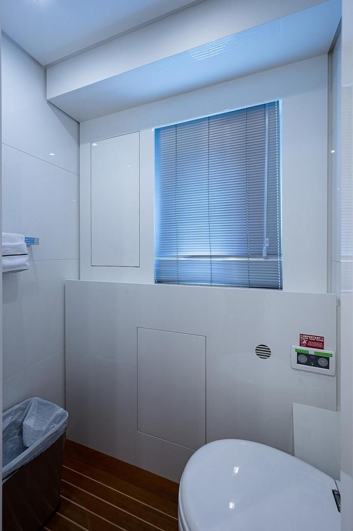 a bathroom with a toilet and a window aboard CASSINELLA Yacht for Sale