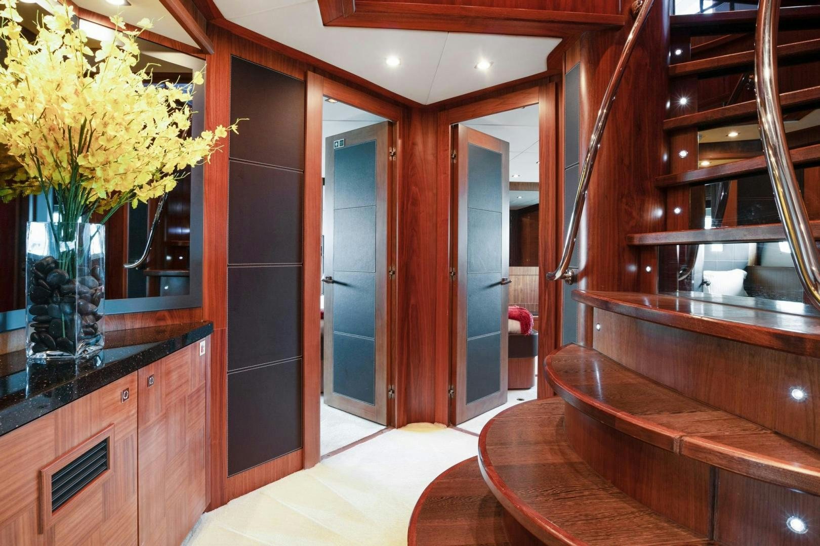 a room with wooden stairs and a vase of yellow flowers aboard ACACIA Yacht for Sale