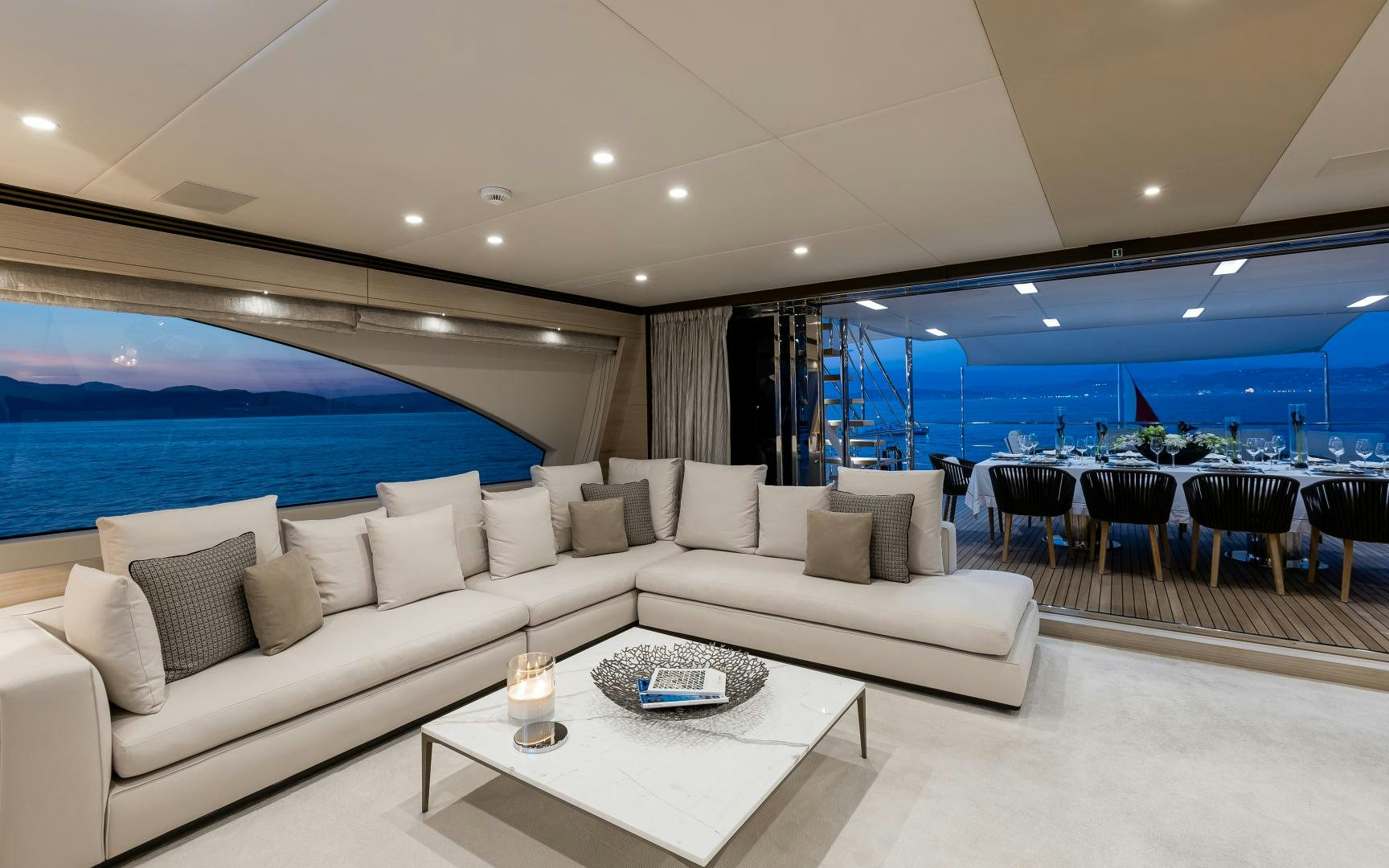 a living room with a large white sofa and a large blue ocean aboard JACOZAMI Yacht for Sale