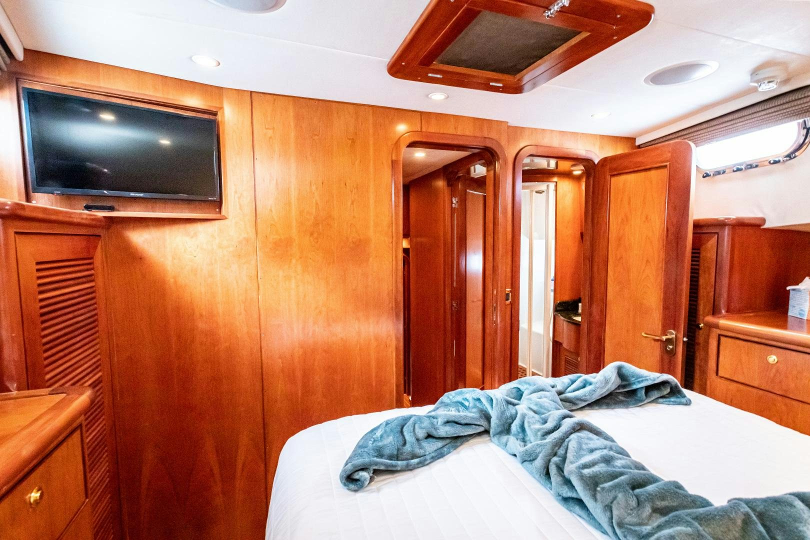 a bedroom with a television and wooden cabinets aboard TJ SQUARED Yacht for Sale