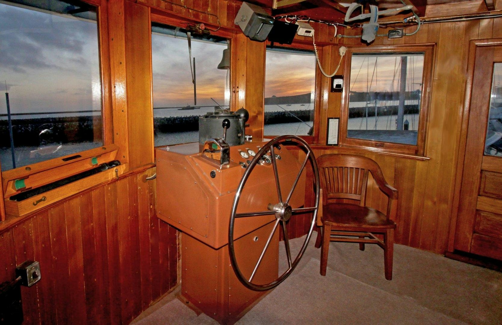 a wooden cabin with a chair and a wheel aboard SACAJAWEA Yacht for Sale