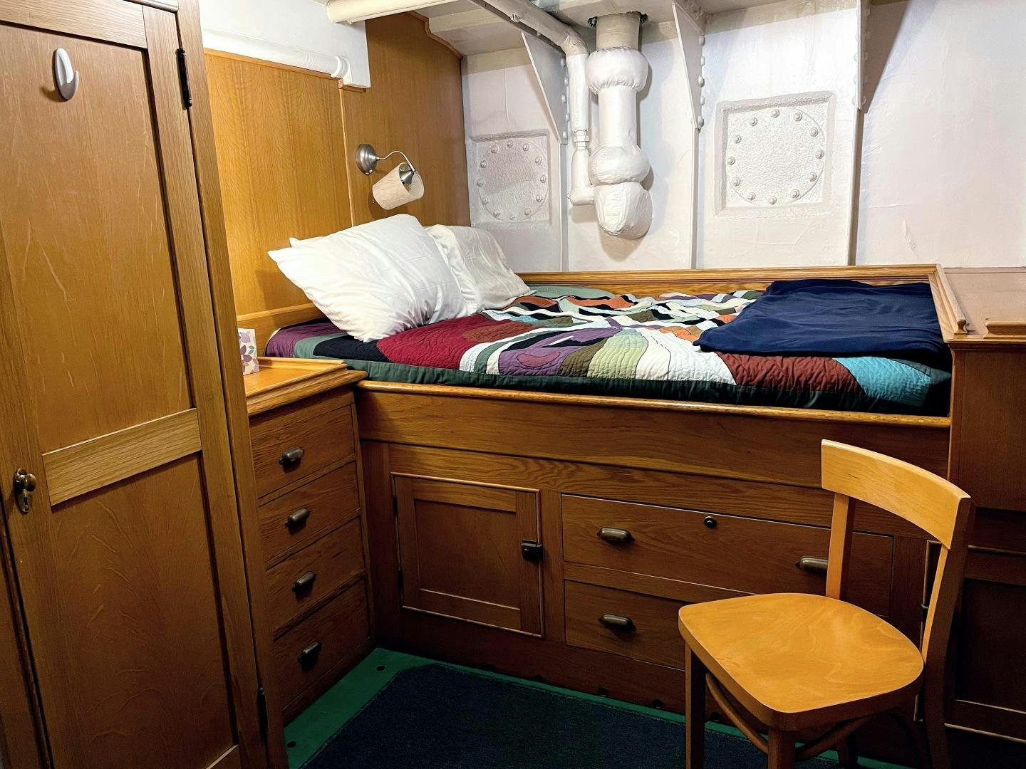 a bedroom with a bed and a chair aboard SACAJAWEA Yacht for Sale
