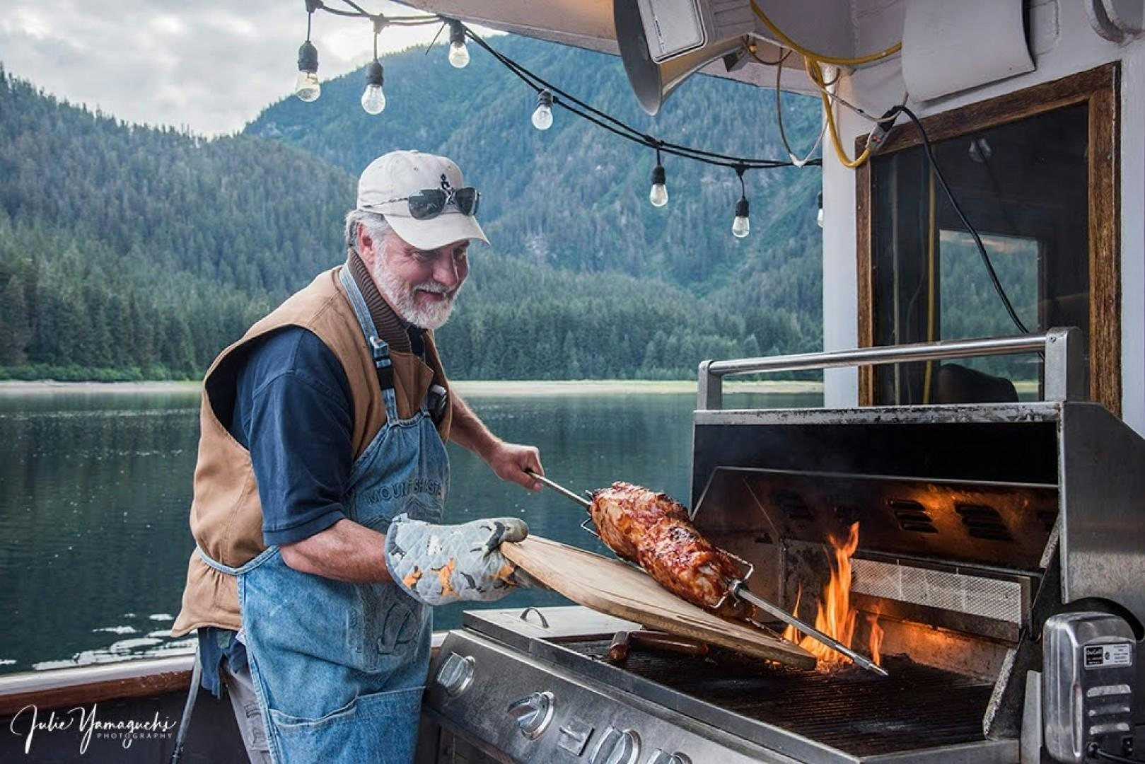 a man grilling meat on a grill aboard SACAJAWEA Yacht for Sale