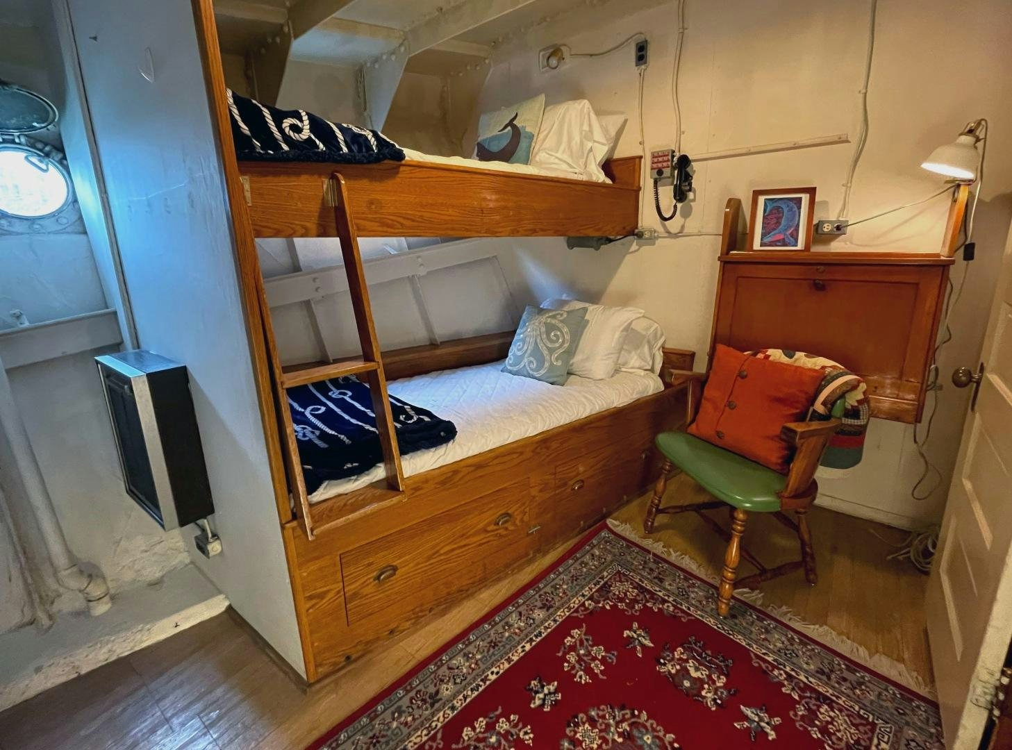 a bed with a chair and a desk in a room aboard SACAJAWEA Yacht for Sale