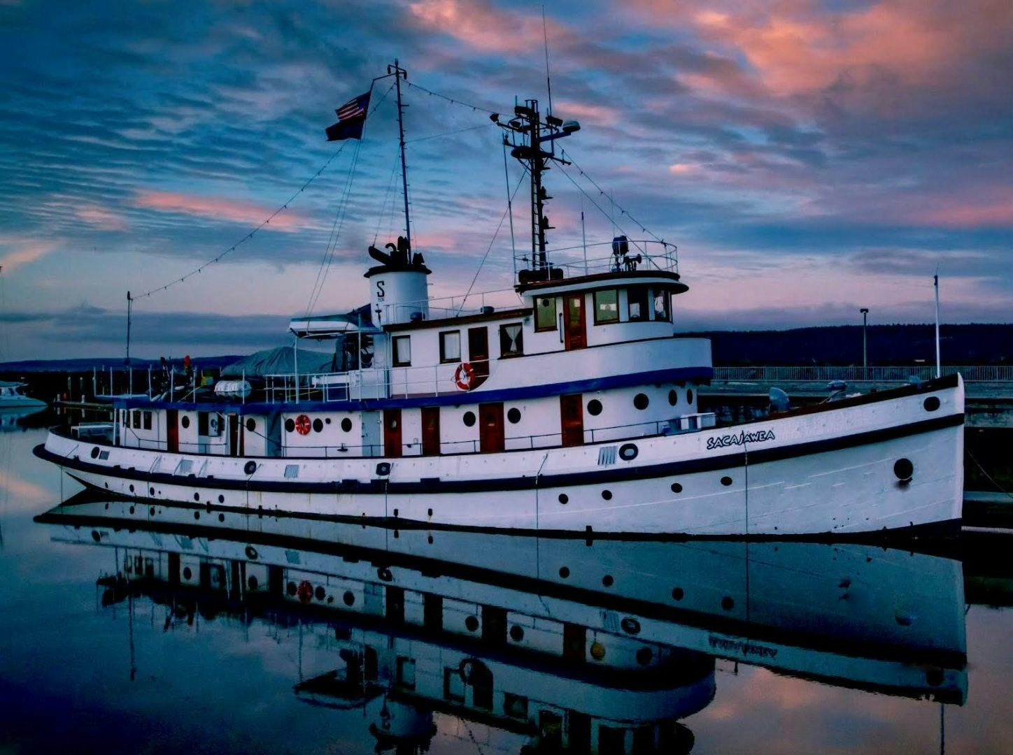 a large white boat with a flag on it aboard SACAJAWEA Yacht for Sale