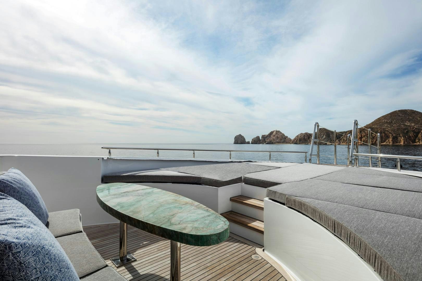 a deck with a view of the ocean and mountains in the background aboard CHAMPAGNE SEAS Yacht for Sale