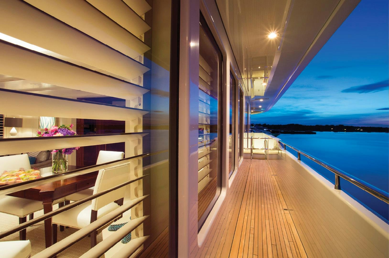 a room with a wood floor and a wood deck with white chairs and a large body of water aboard RHINO Yacht for Sale