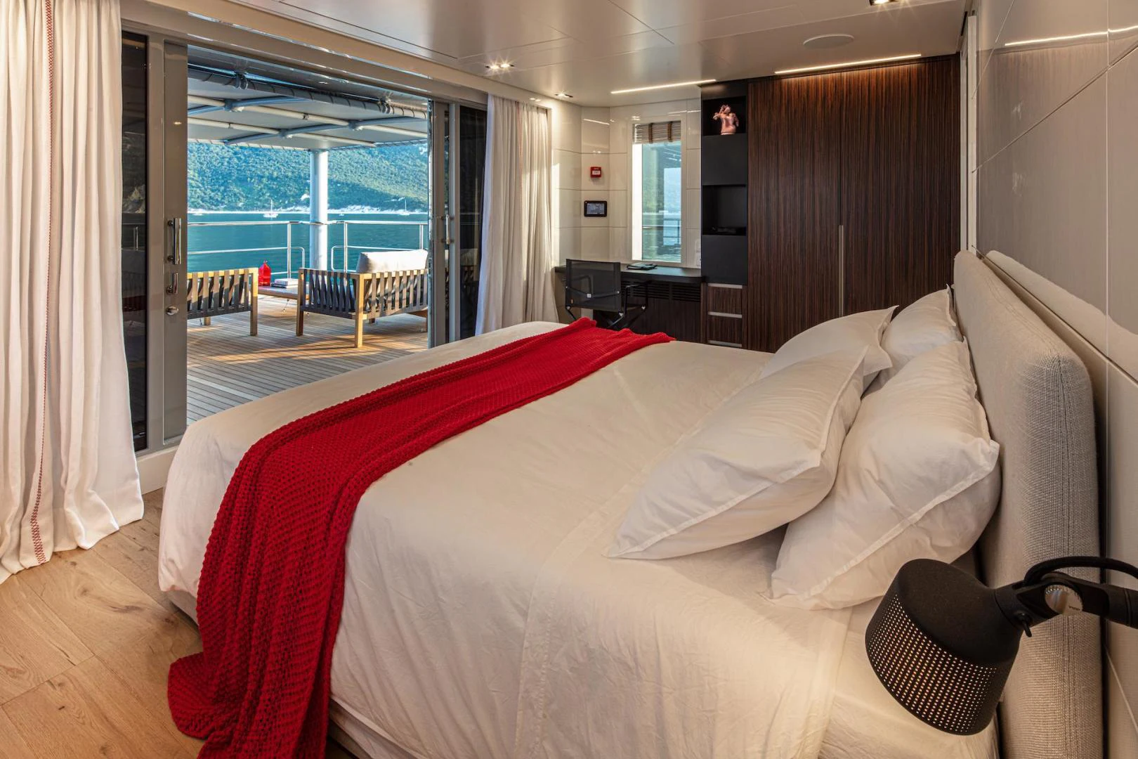 a bed with a red and white bed spread aboard ATOM Yacht for Sale