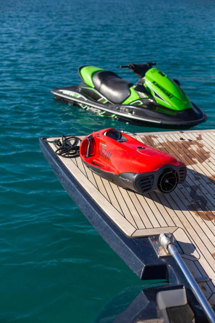 a red and green boat on a dock with a green and black boat on it aboard AZIZAM Yacht for Sale