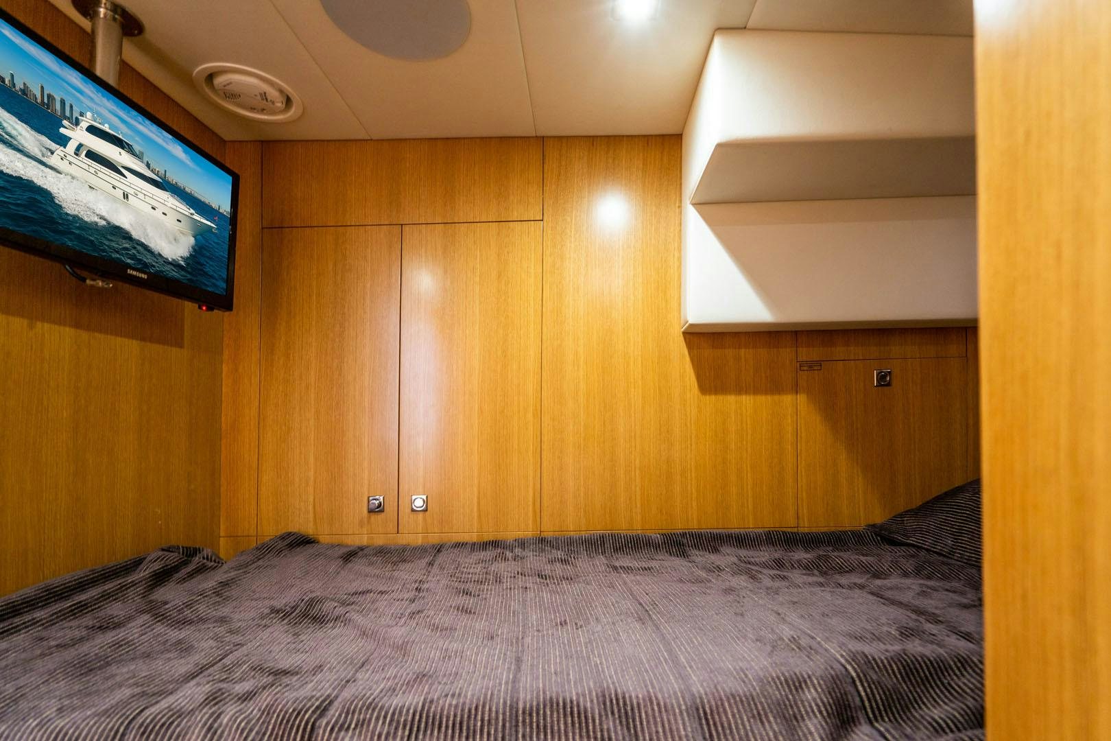 a bed with a television on the wall aboard LIFE Yacht for Sale