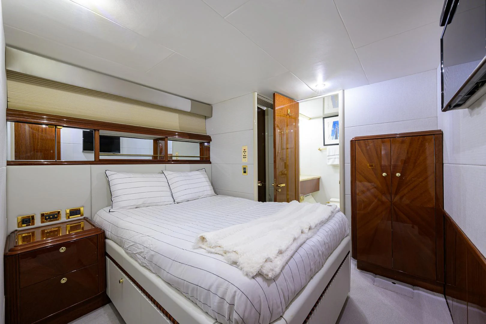 a bedroom with a bed and a wood cabinet aboard TRYST Yacht for Sale