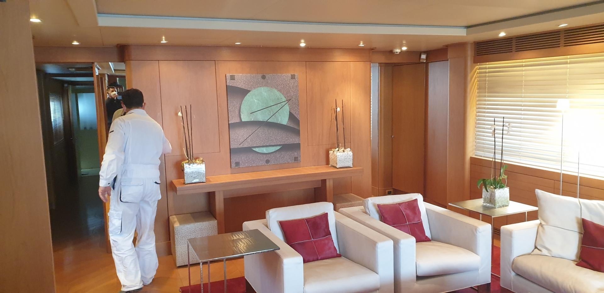 a person in a white coat standing in a room with a large painting on the wall aboard TIGRA Yacht for Sale