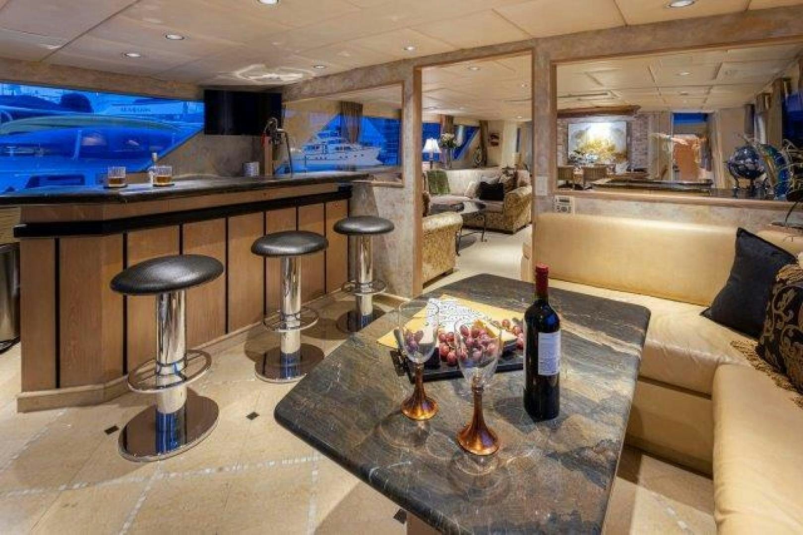 a bar with stools and a table with a glass of wine aboard ANDIAMO Yacht for Sale