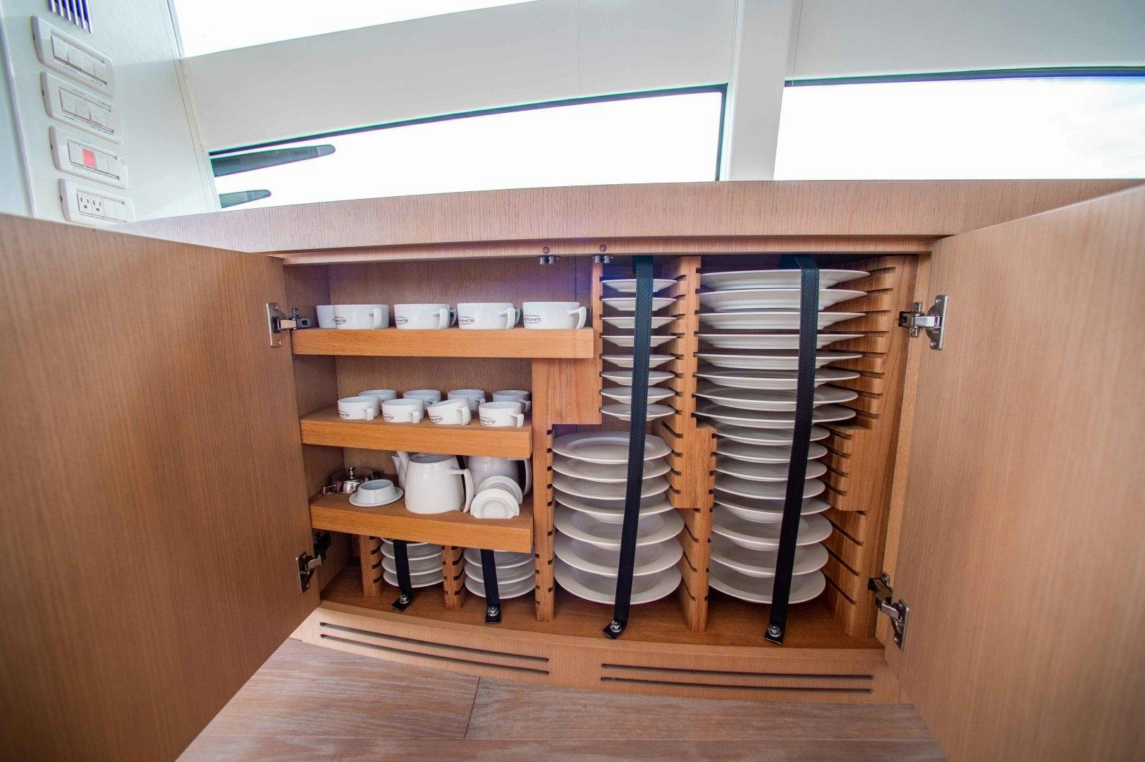 a wooden cabinet with a shelf of dishes and a dishwasher aboard JULIE K Yacht for Sale