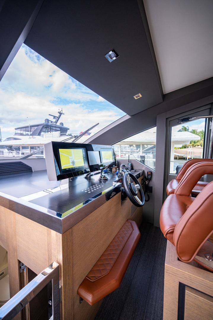 a person's hand holding a phone in front of a window with a view of the water aboard LEBRADA Yacht for Sale