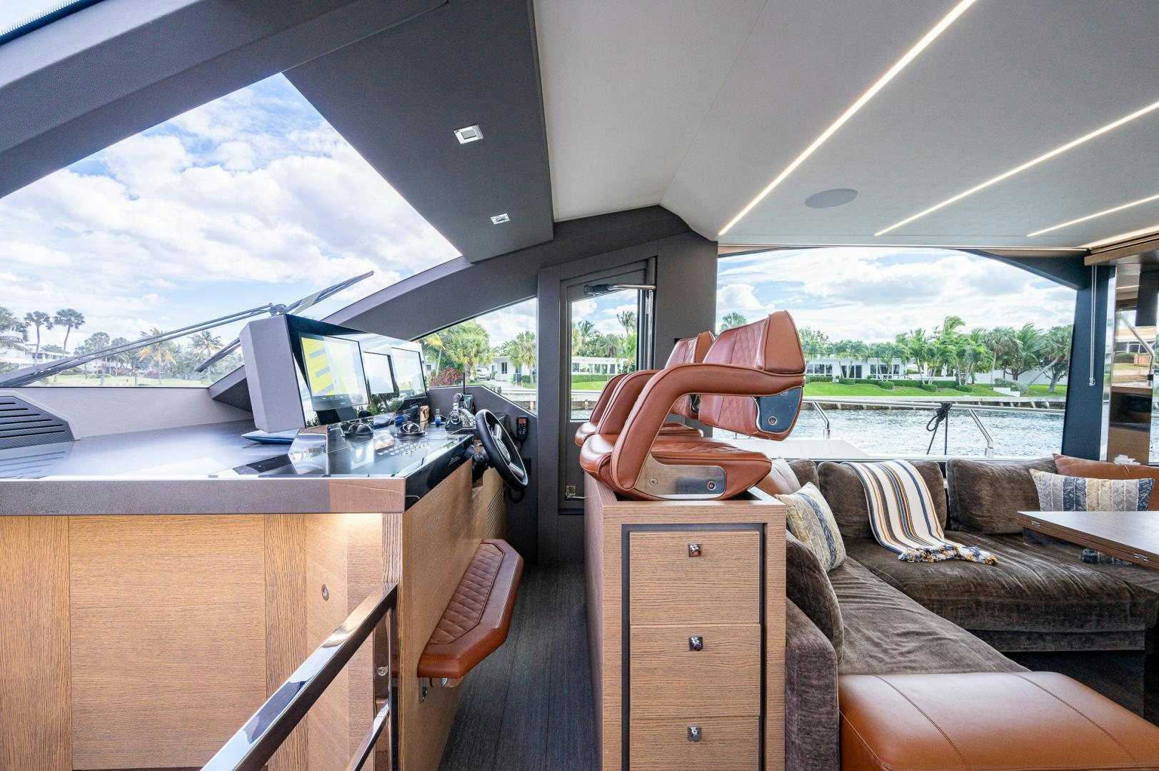 a person's hand on a chair in a room with a view of the water and trees aboard LEBRADA Yacht for Sale