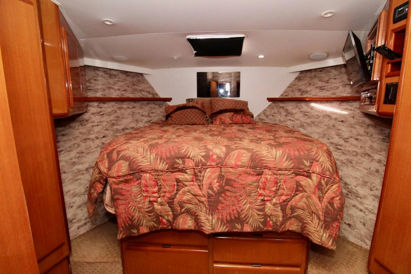 a bedroom with a bed and a television on the wall aboard BAD TO THE BONE Yacht for Sale
