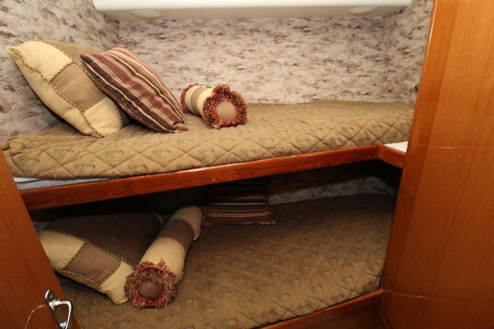 a bed with a brown blanket and a red pillow on it aboard BAD TO THE BONE Yacht for Sale