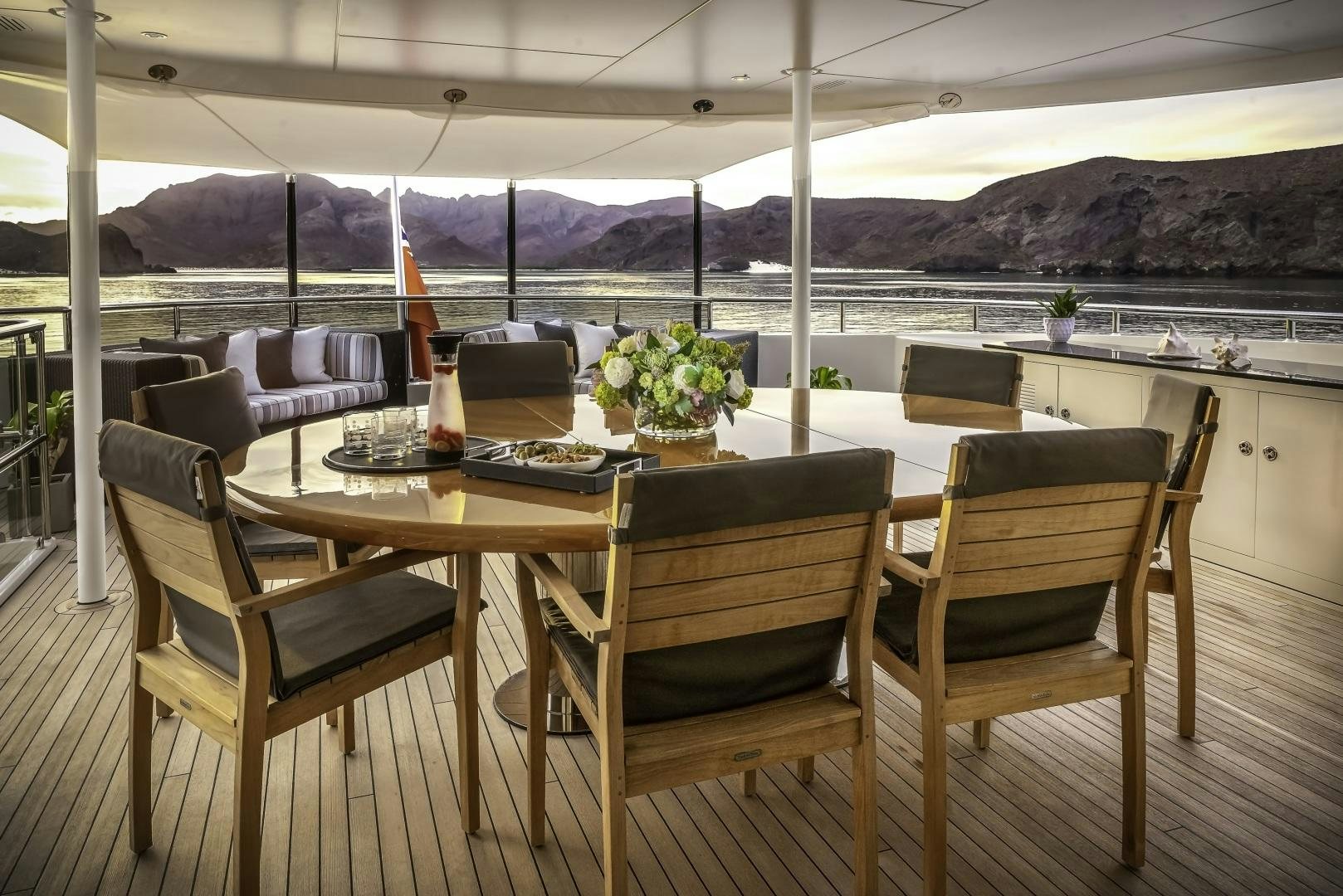 a table set with chairs and a view of mountains aboard ODYSSEA Yacht for Charter
